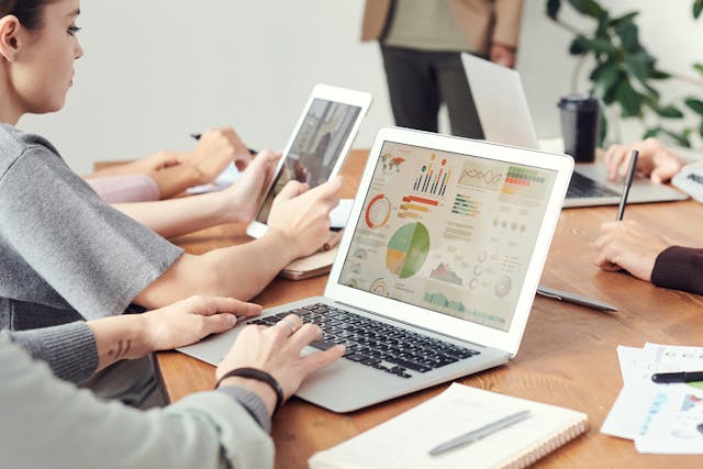 A freelance seo expert reviewing data visualizations and website traffic charts on a laptop during a team strategy meeting.